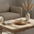 Minimalist round hand-woven rattan tray on a light wood coffee table, featuring a ceramic cup and book in a sunlit living room - Serein Home.
