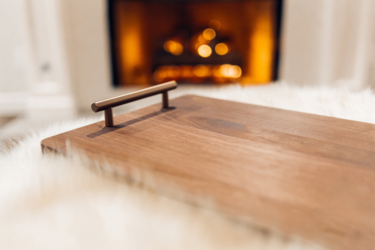 Walnut serving and cutting board with bronze handles on a wooden table