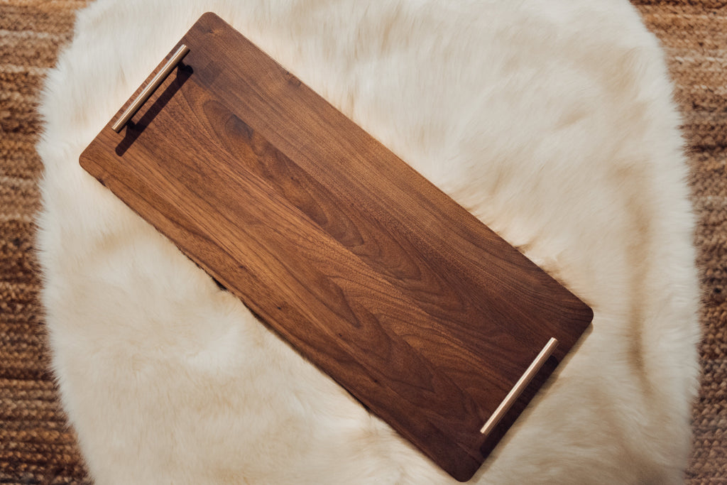 XL walnut charcuterie board with bronze handles displayed on neutral fabric