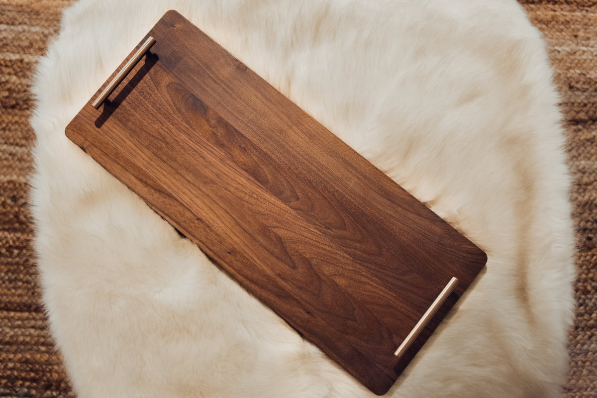 XL walnut charcuterie board with bronze handles displayed on neutral fabric