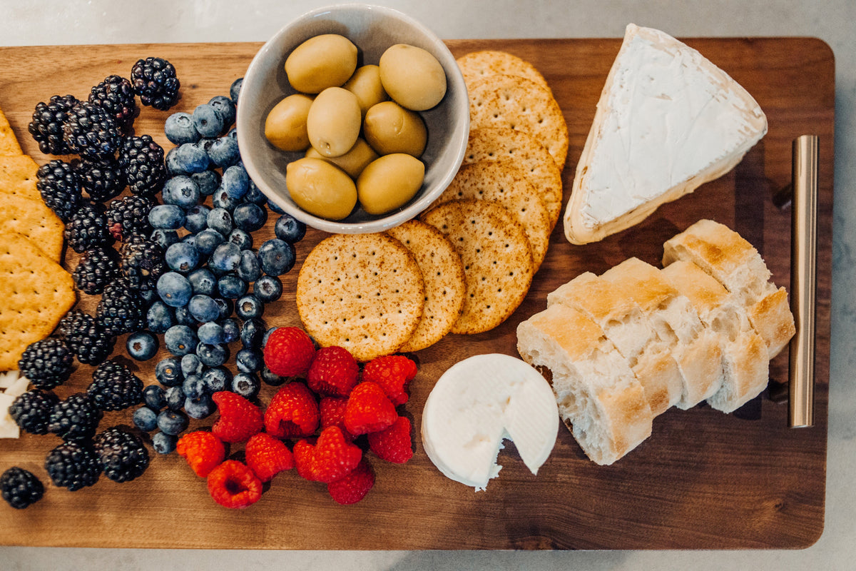 XL walnut charcuterie board styled with cheese, fruit, crackers and olives