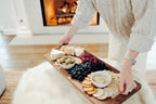 Person arranging food on an XL walnut charcuterie and cutting board