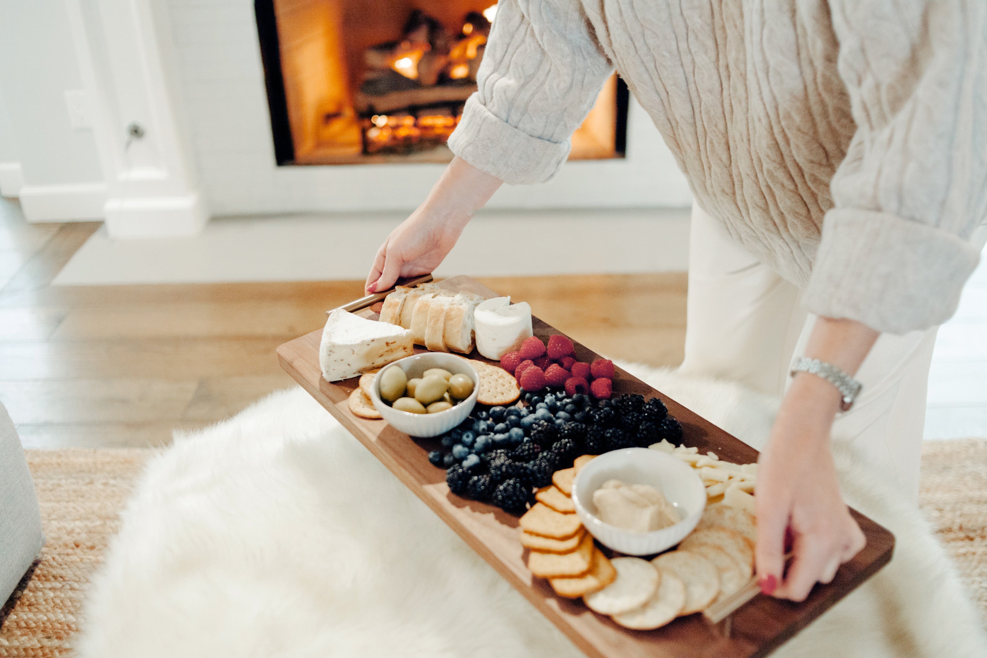 Person arranging food on an XL walnut charcuterie and cutting board