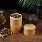 Open bamboo tea canister filled with rolled green tea beside its lid and a clay teapot, Serein Home