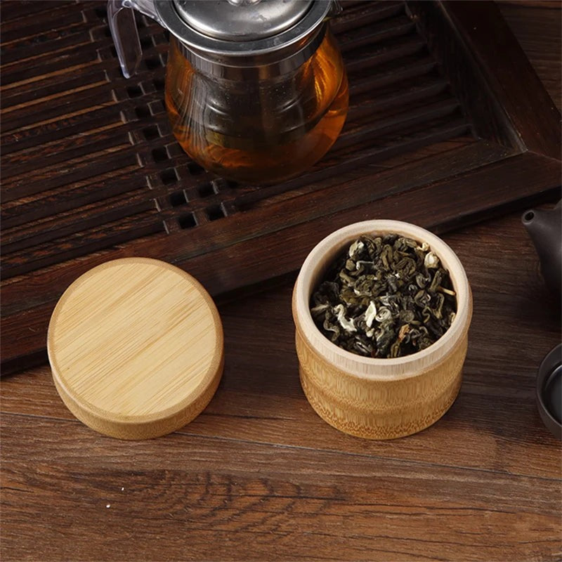 Bamboo tea canister with the lid set aside, loose green tea inside, glass teapot behind, Serein Home