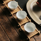 Three white octagonal tea cups on bamboo cup mats in a row on rustic wood, Serein Home