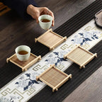 Bamboo tea coasters laid along a blue and white table runner, one with a cup, Serein Home