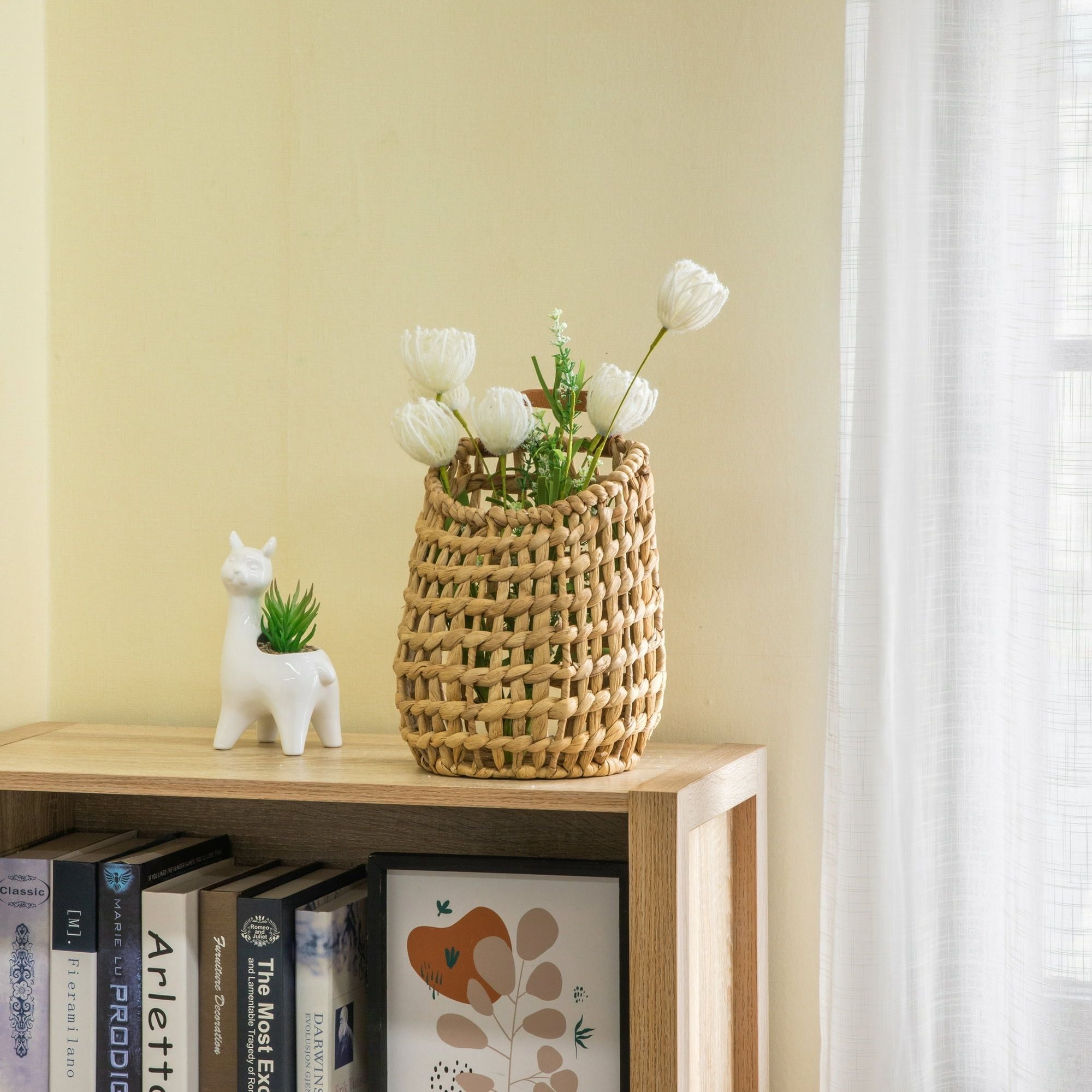 Woven basket with flowers on a wooden shelf against a light yellow wall.