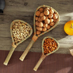Bamboo strainer scoops holding walnuts, pistachios and almonds beside an orange, Serein Home
