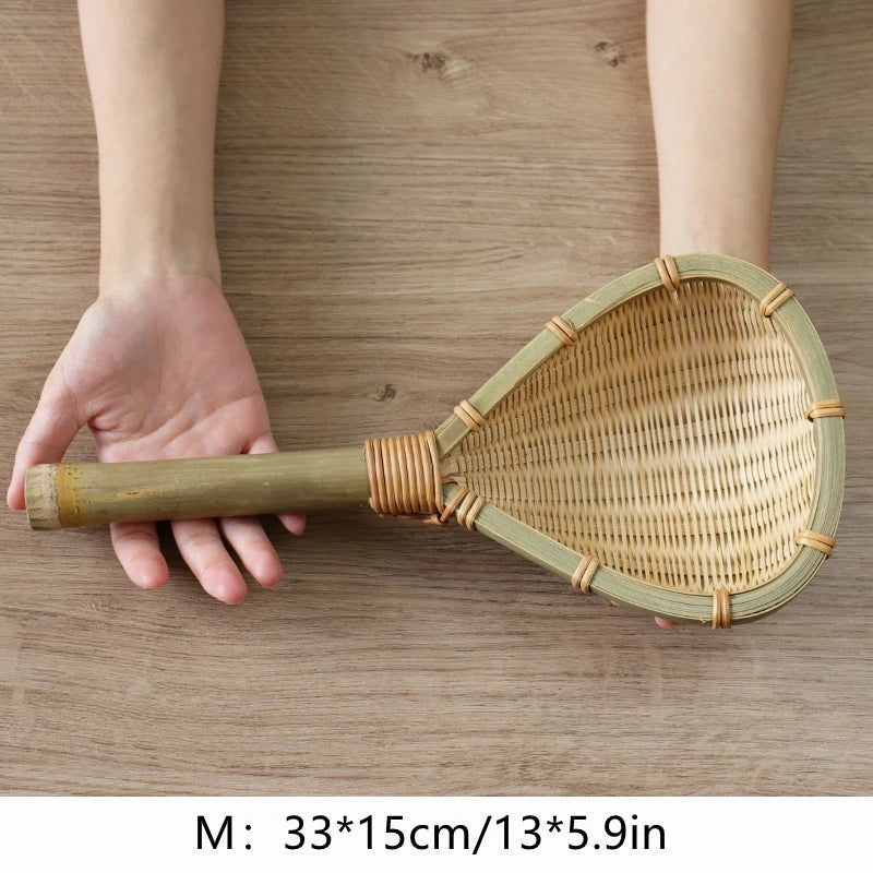 Medium 33 cm bamboo strainer with bamboo handle held in one hand over a table, Serein Home