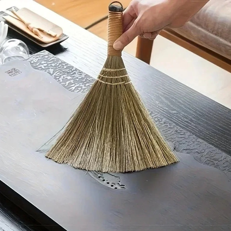 Grass table broom lying on a dark wooden dining table