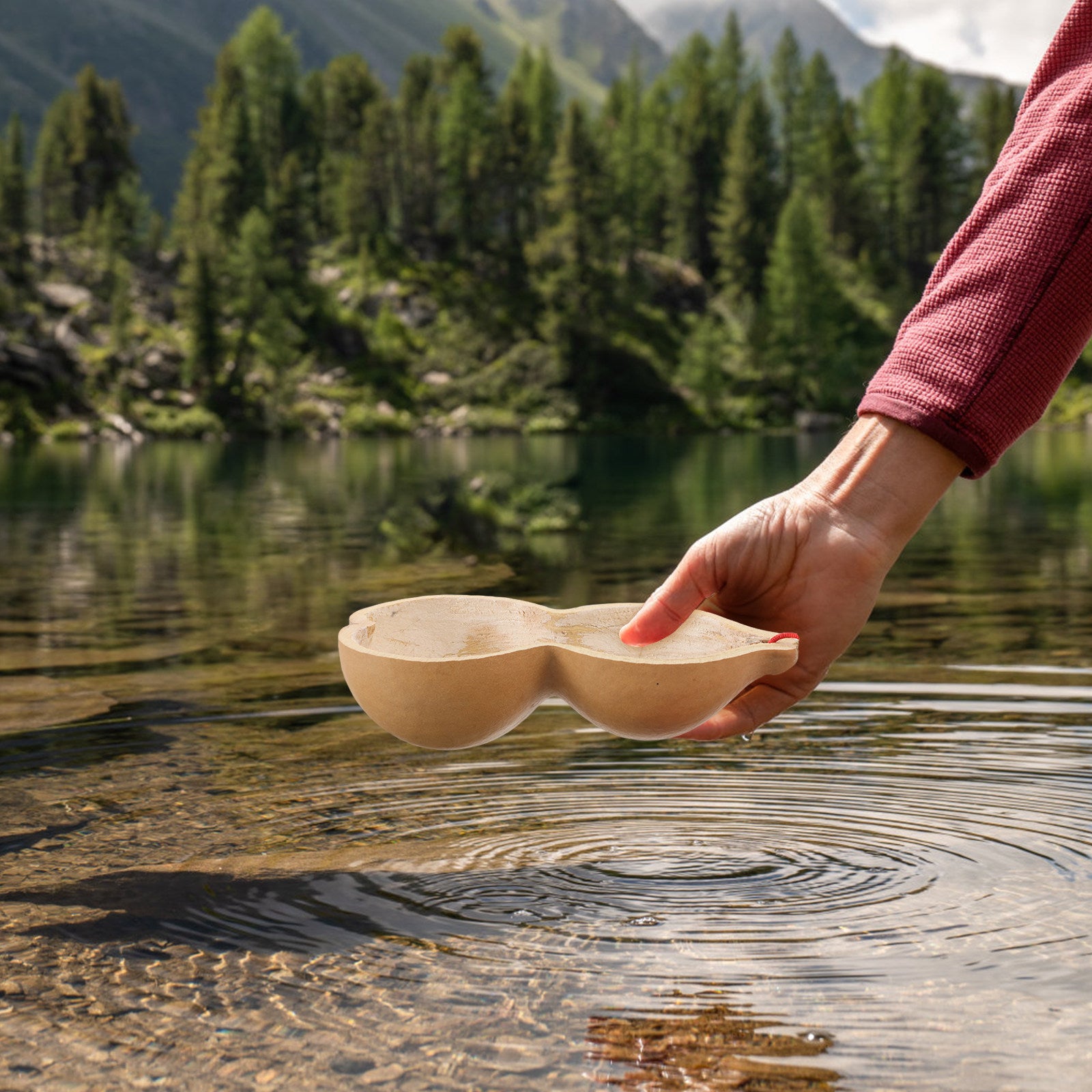 Hand setting a gourd water dipper on the surface of a mountain lake