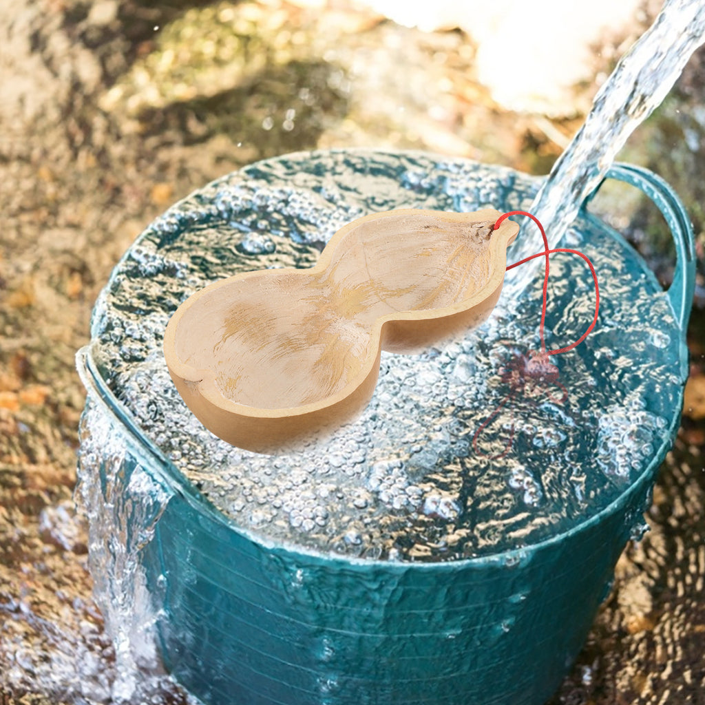 Gourd water dipper floating in a teal bucket as water pours in