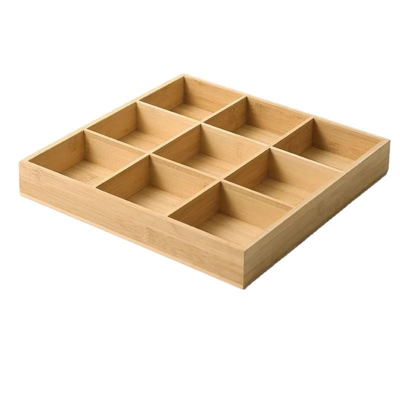 Empty nine-compartment bamboo snack tray at an angle on a white background