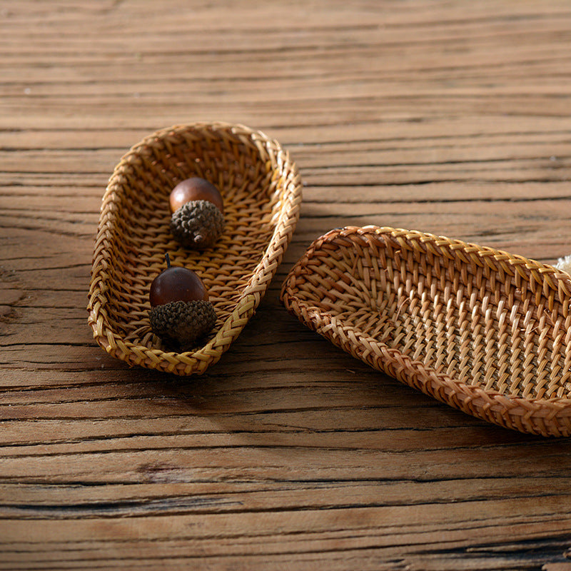 Oval wild rattan tray holding a small candle on wooden countertop with natural home decor
