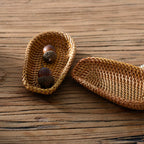 Oval wild rattan tray holding a small candle on wooden countertop with natural home decor