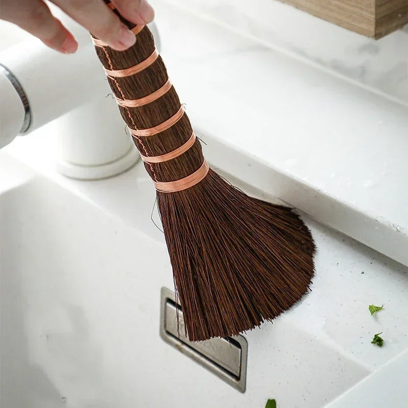 Palm fiber brush sweeping water from a white kitchen sink, showing its fanned bristles, Serein Home