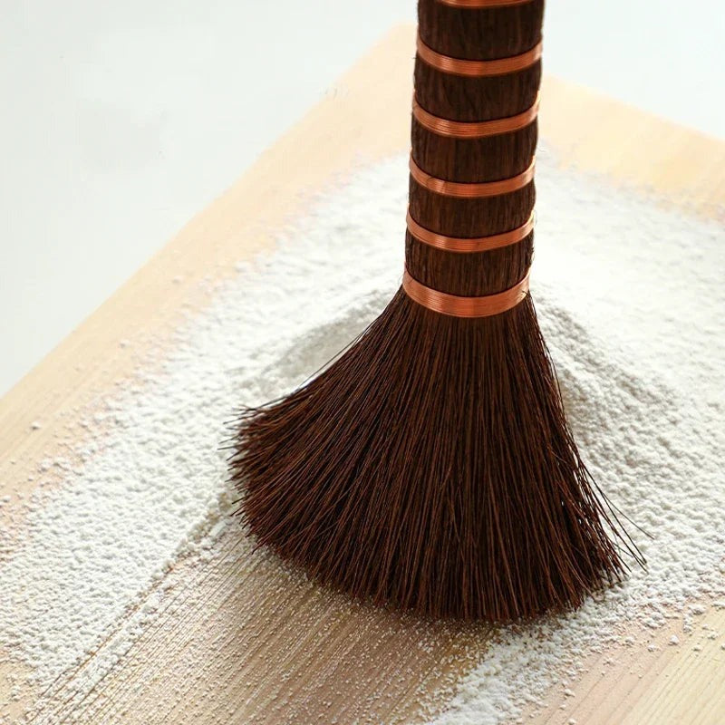 Close-up of palm bristles and copper wire bands brushing flour off a cutting board, Serein Home