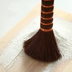 Close-up of palm bristles and copper wire bands brushing flour off a cutting board, Serein Home