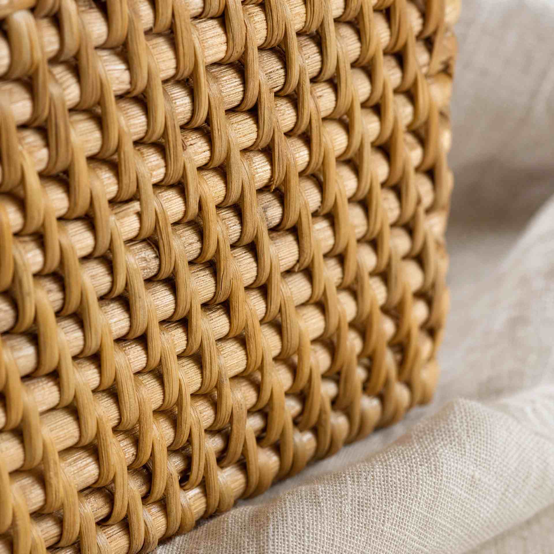 Close-up of natural rattan weave texture — honey-tan over-under
  fiber pattern with soft side light, Serein Home