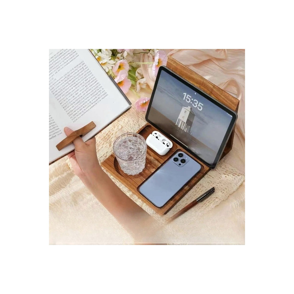 Wood book stand holding a tablet beside a glass and phone, hand using the wooden page holder