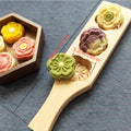 Carved wooden mooncake press mold beside pressed flower mooncakes