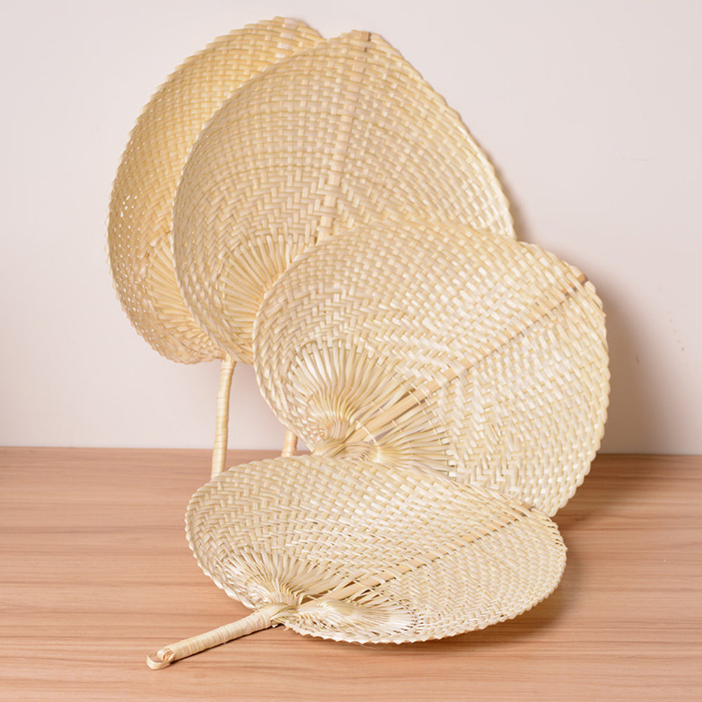 Row of undyed woven palm leaf fans on a pale wooden floor