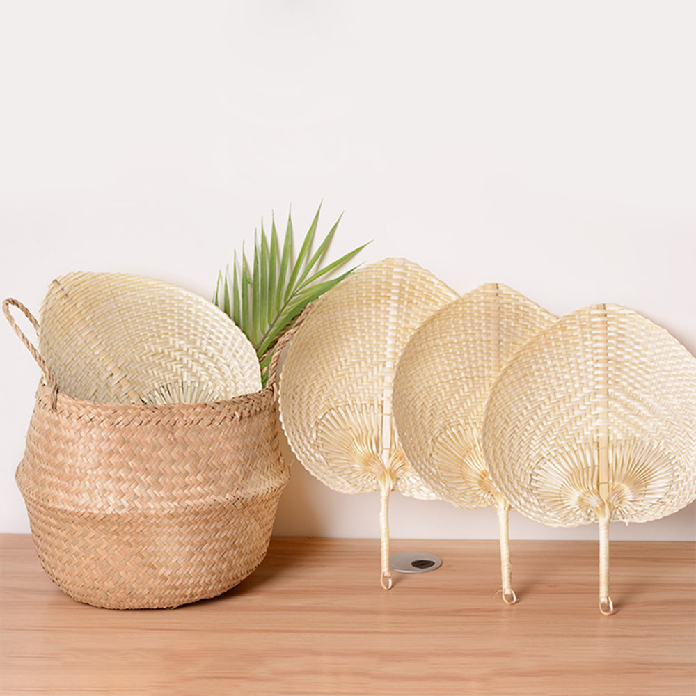 Woven palm leaf fans in and beside a seagrass basket with a palm frond
