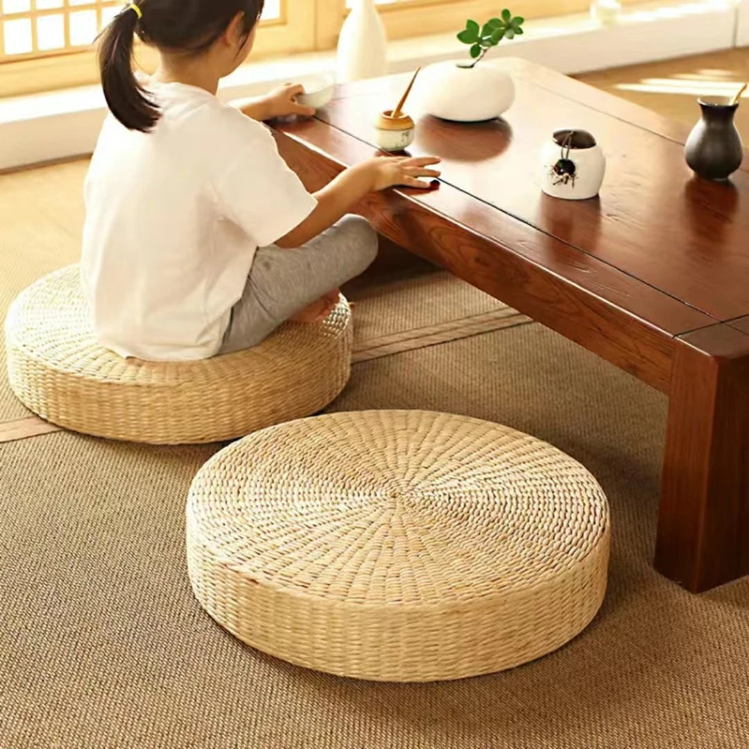 Child sitting on a woven straw cushion at a low wooden table, a second cushion beside her, Serein Home
